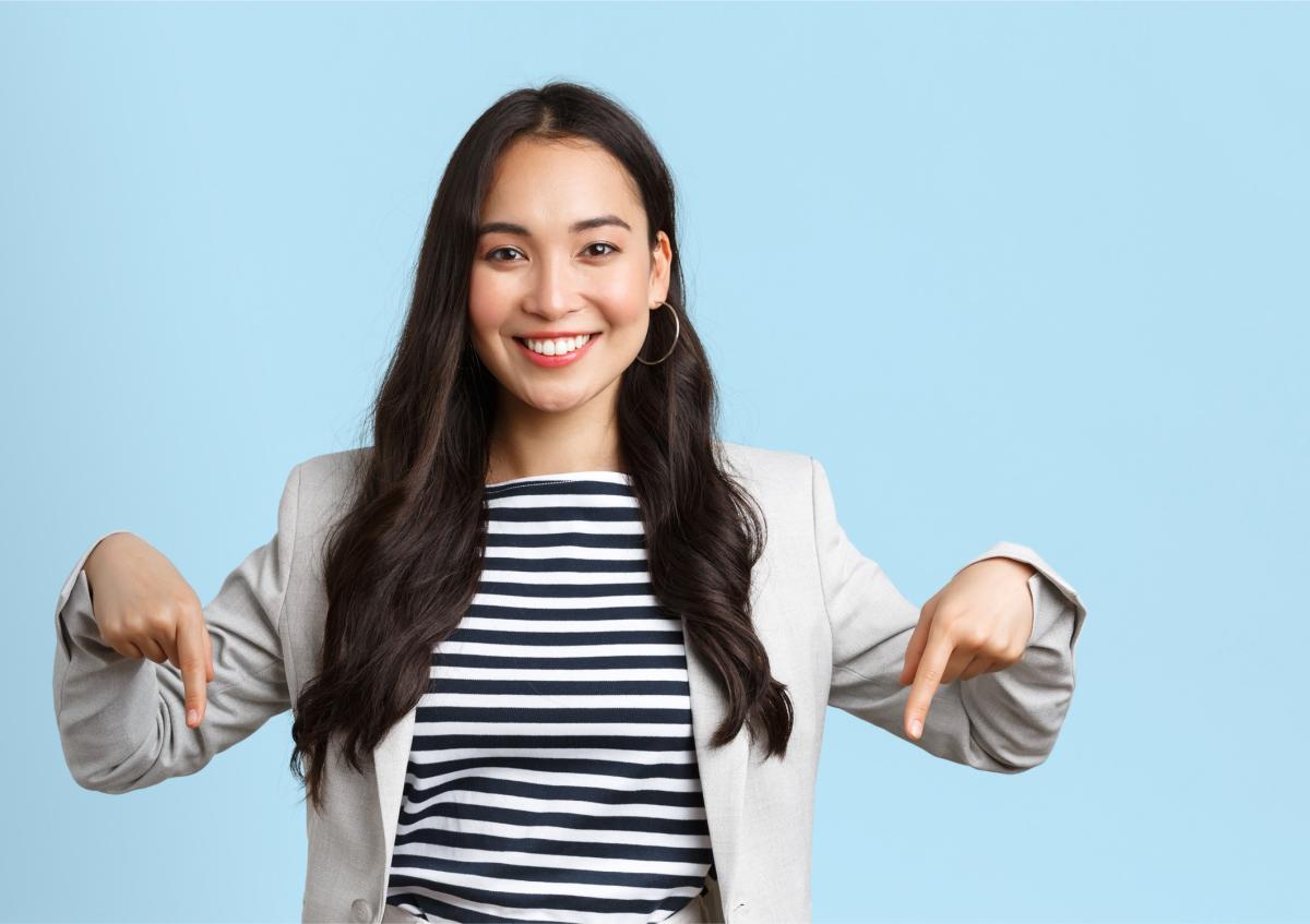 Jonge vrouw wijst naar beneden met beide wijsvingers