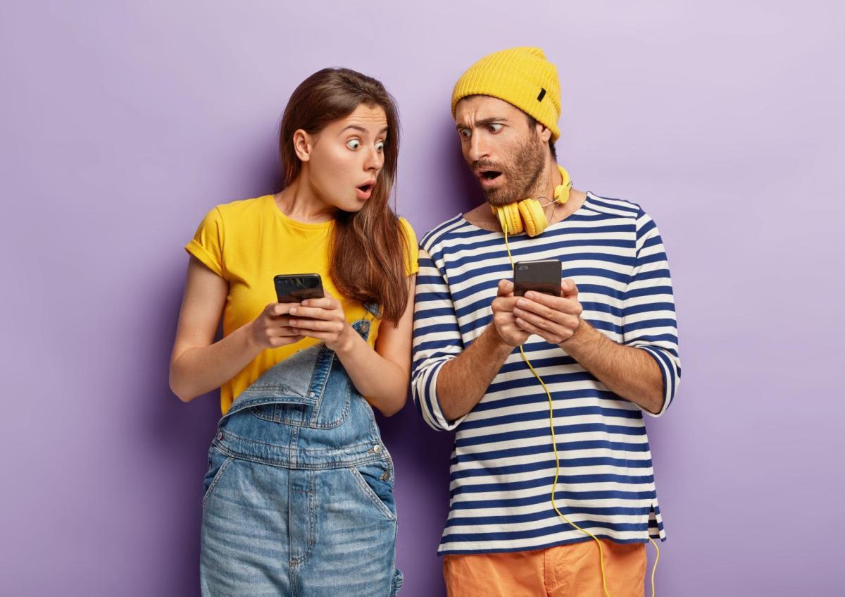 Two surprised people looking at their phones with shocked expressions.