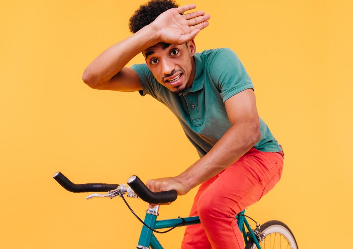 A young man looks anxious or scared, holding the handlebars of his bike tightly with one hand