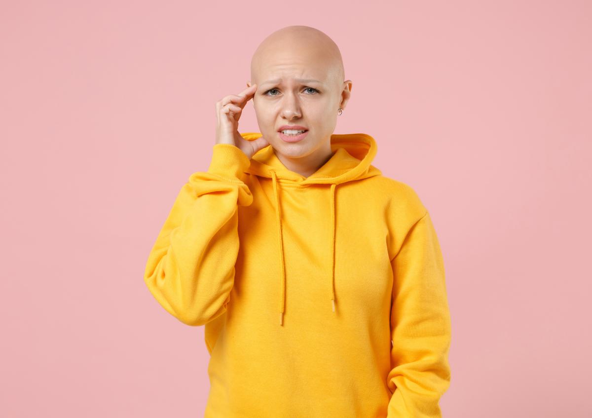 A worried or stressed young woman touching her temple, expressing concern or headache.