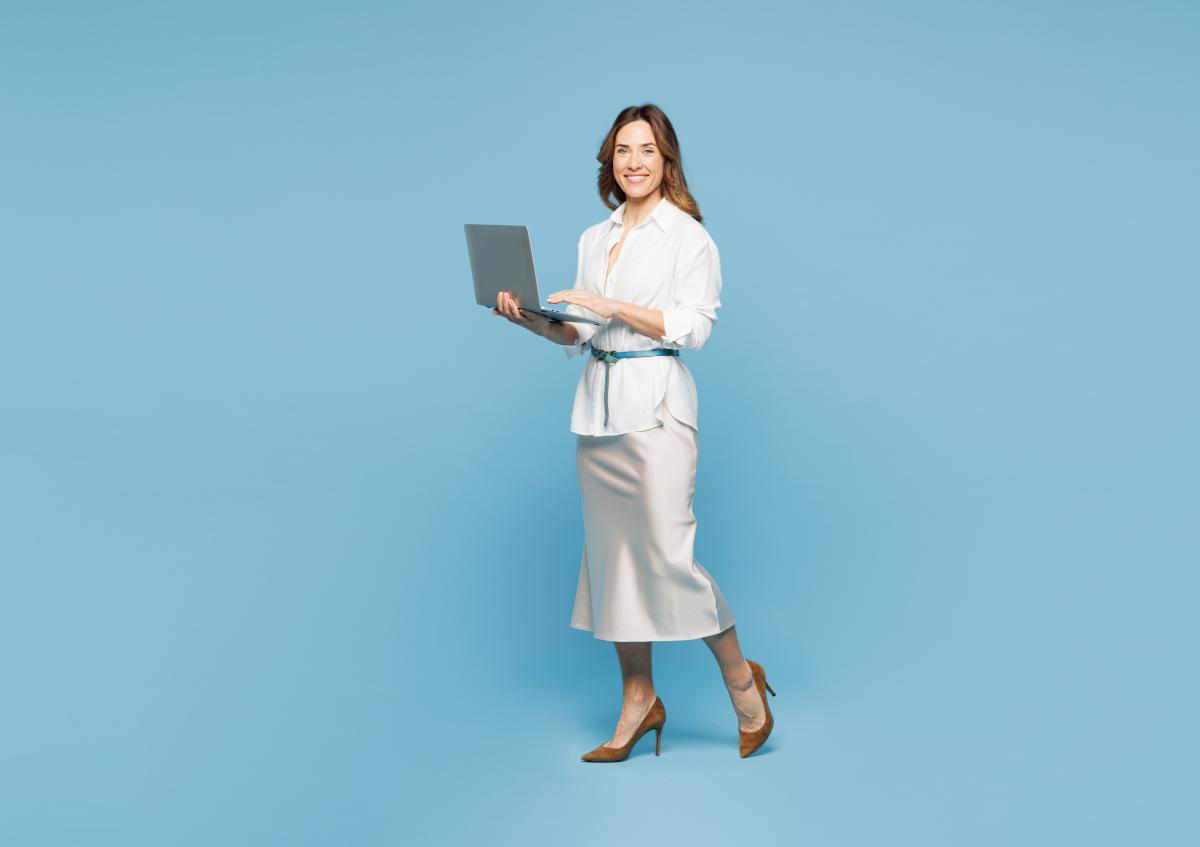 Een jonge vrouw houdt een laptop in haar handen, terwijl ze zelfverzekerd glimlacht.