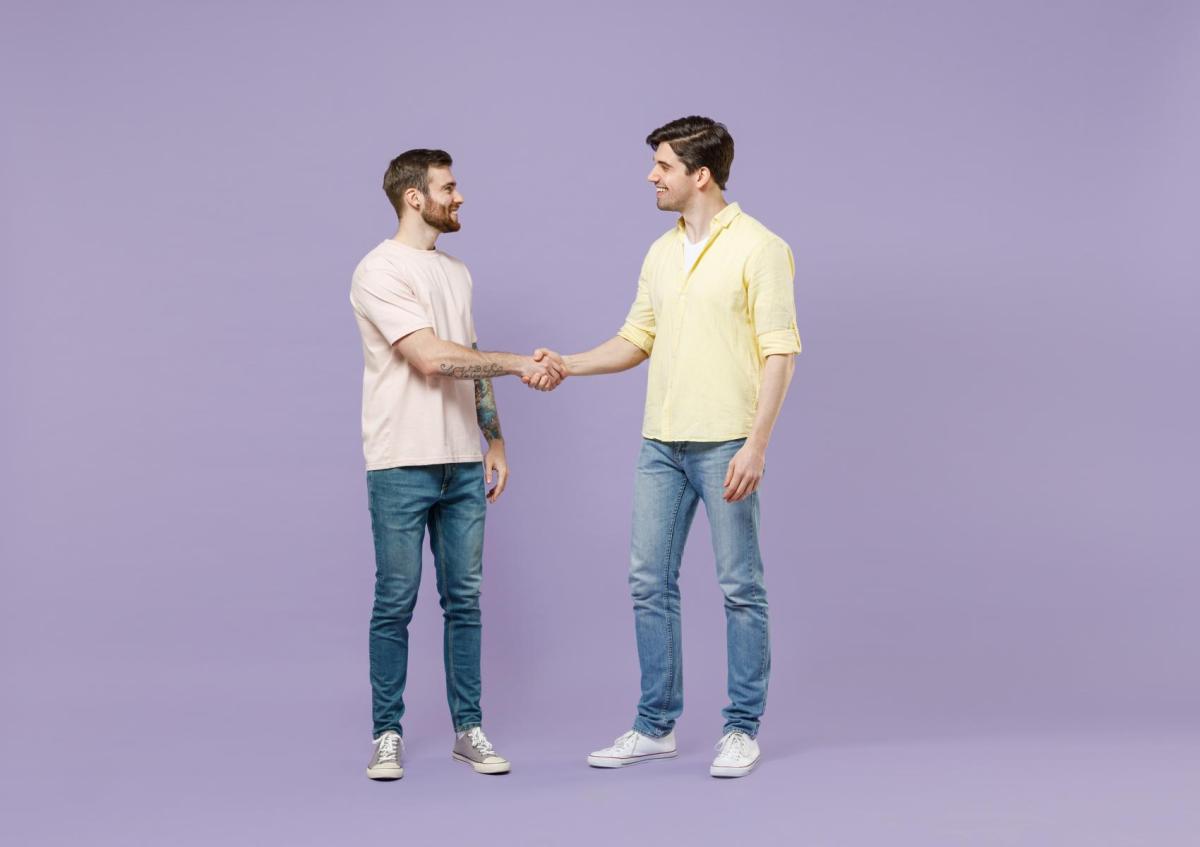 Twee mannen staan tegenover elkaar, glimlachen en schudden elkaar de hand.