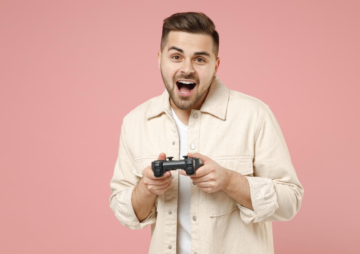 Een man houdt een gamecontroller met beide handen vast en toont een enthousiaste of verraste uitdrukking.