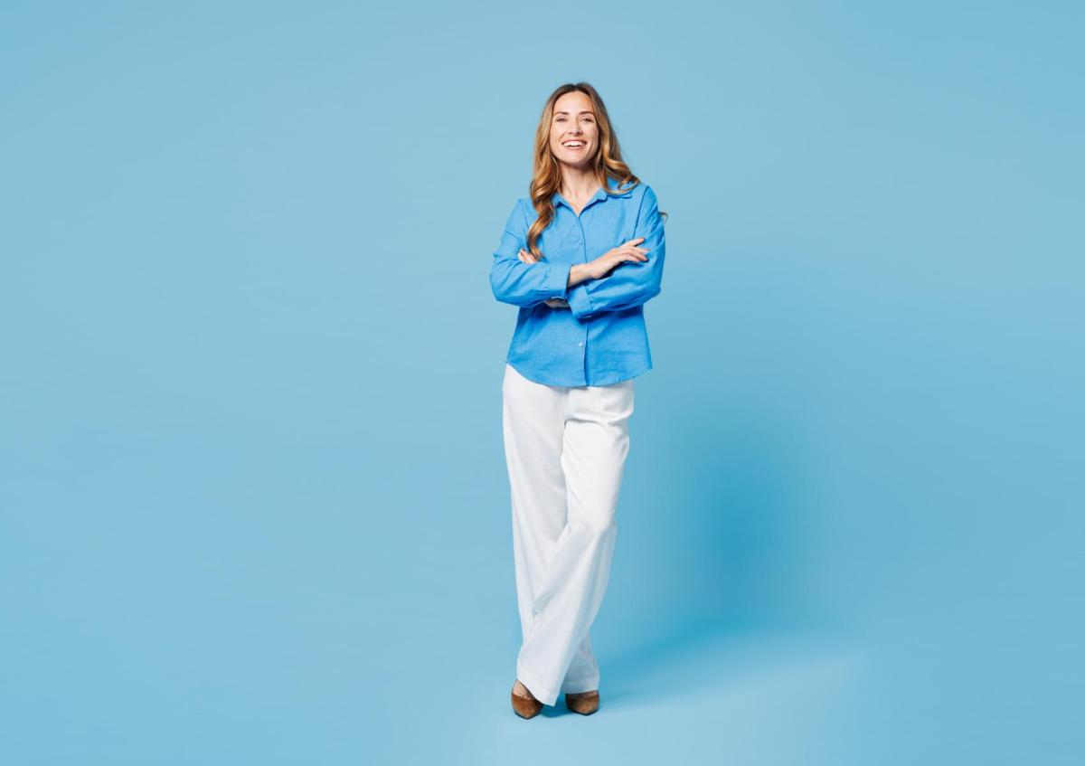 A confident woman smiling warmly with arms crossed