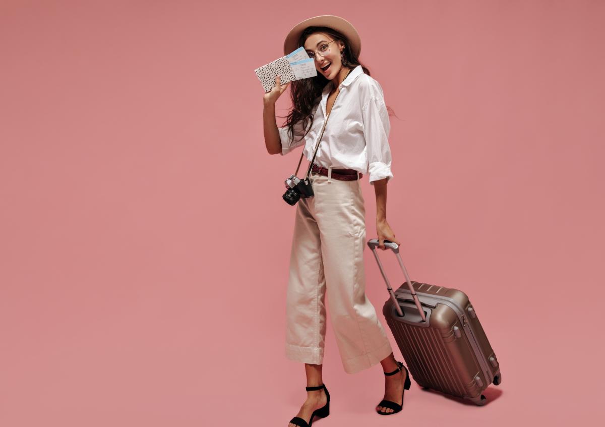 Woman with flight tickets in her hand and a suitcase looks happy