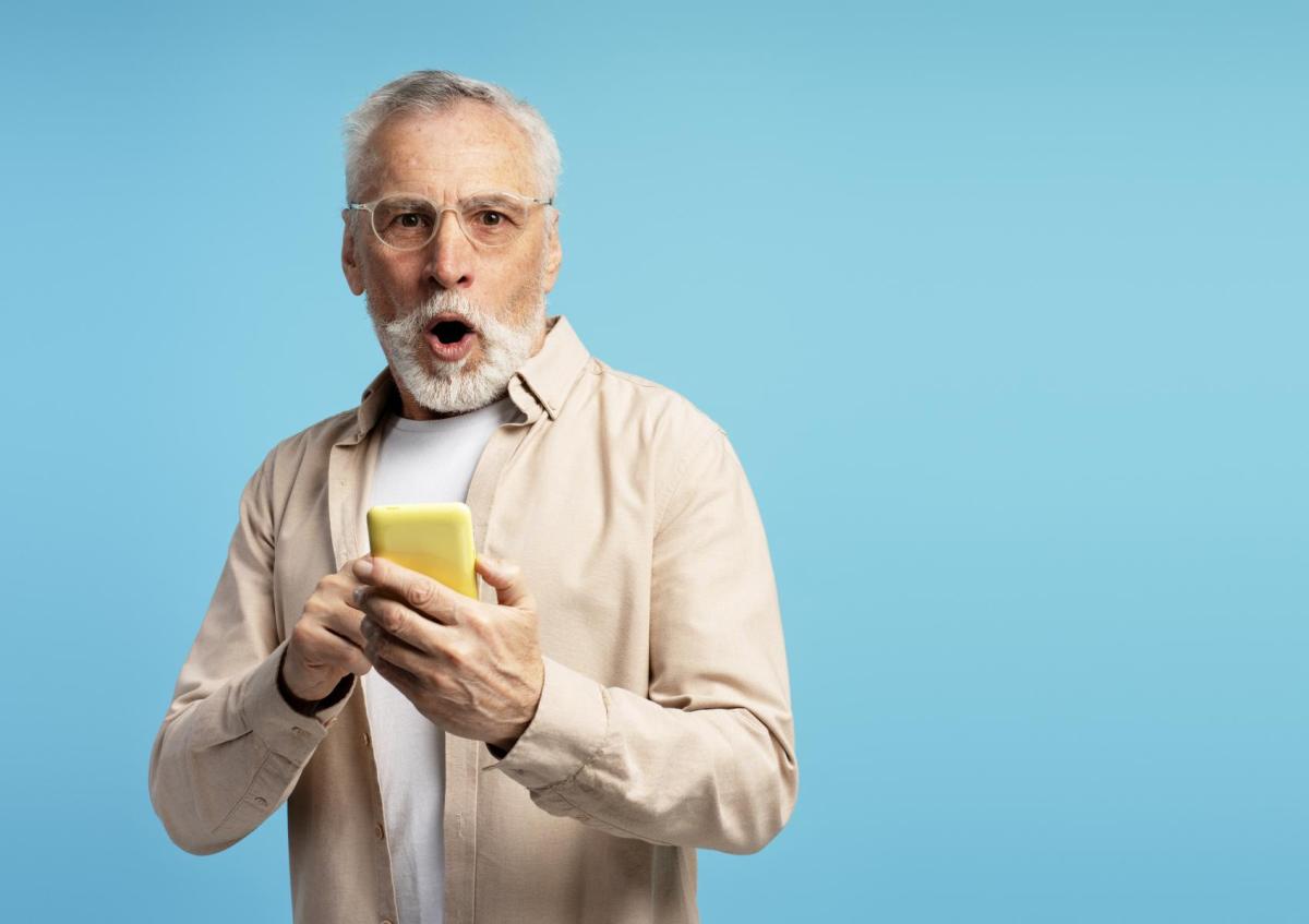 A man holding a mobile phone looks shocked