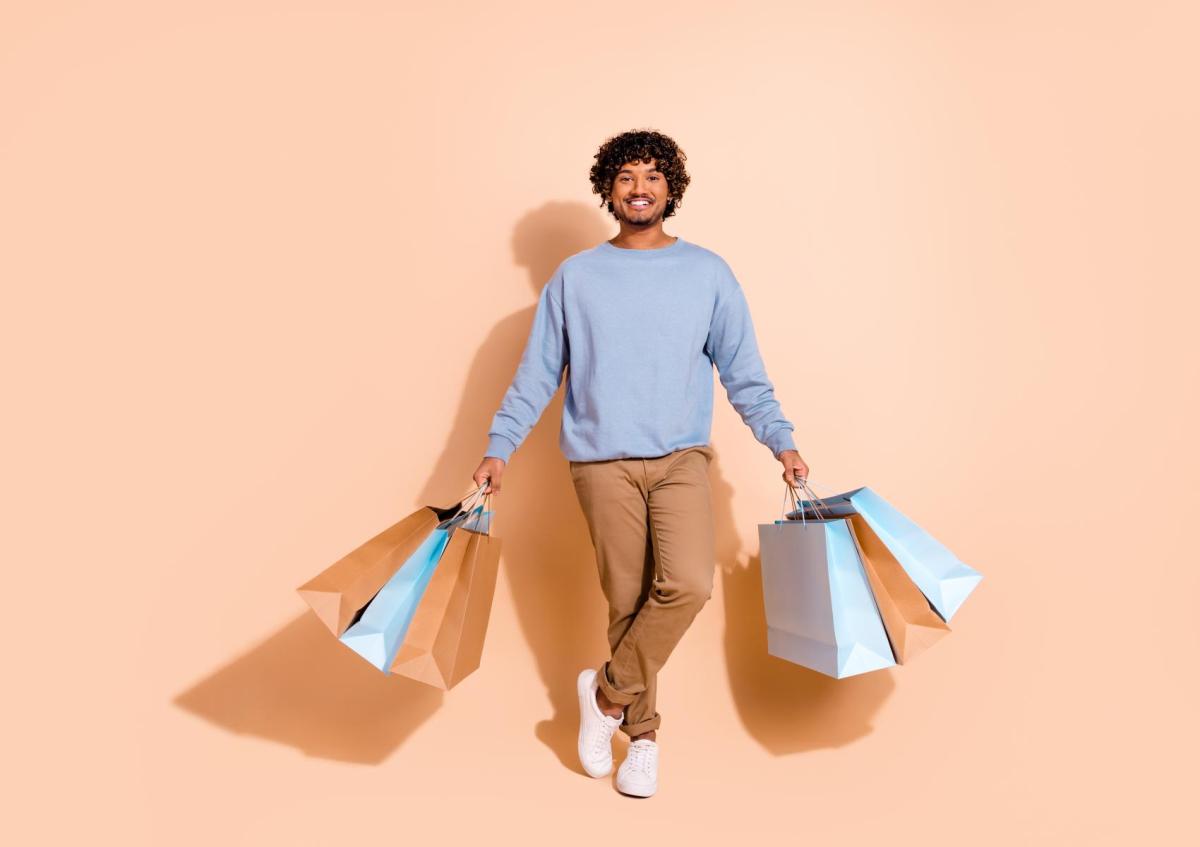 Young man smiling happily while holding multiple shopping bags