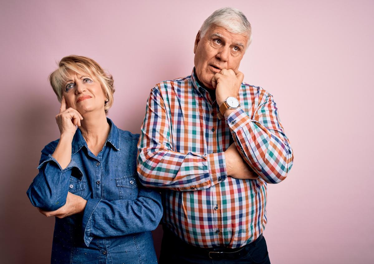 Couple on pink background, disappointed about hotel in travel package
