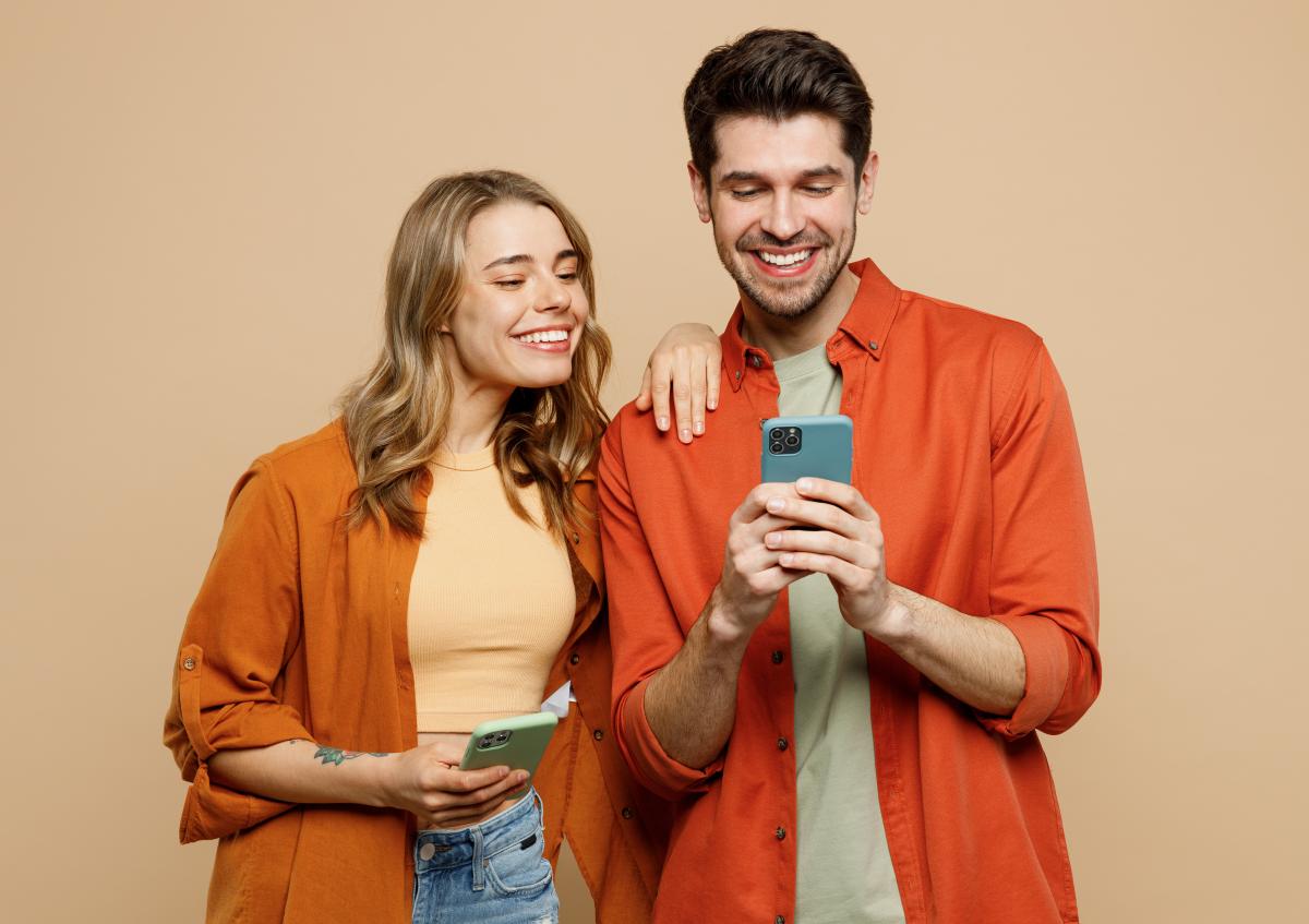 Couple looking at Black Friday Deals on mobile, beige background