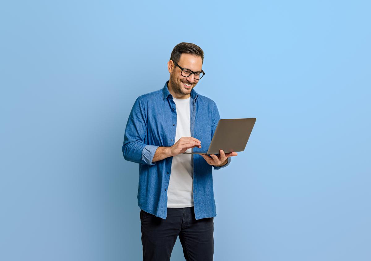 Staande man vraagt terugbetaling aan op laptop, effen, lichtblauwe achtergrond