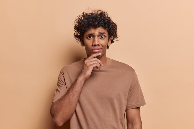 A happy young man and woman smile at the camera. The woman has her arm resting on the man's shoulder and gives a thumbs-up, while the man holds a laptop with one hand and gives a thumbs-up with the other.