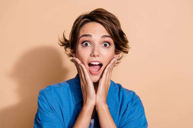 A shocked woman holding her hands to her cheeks 