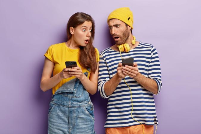 Two surprised people looking at their phones with shocked expressions.
