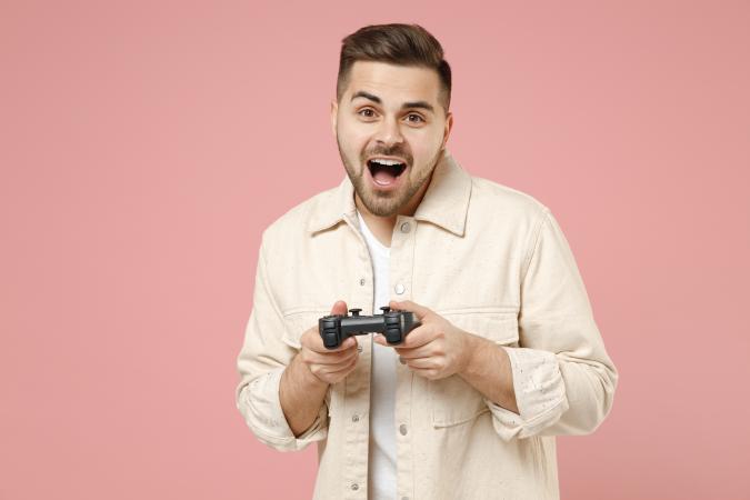 A man holding a video game controller with both hands, expressing excitement or surprise.