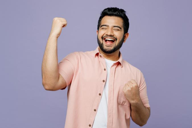 ChatGPT zei: A man smiling broadly with eyes closed, raising one fist in a gesture of celebration or victory, while the other fist is clenched near his chest.