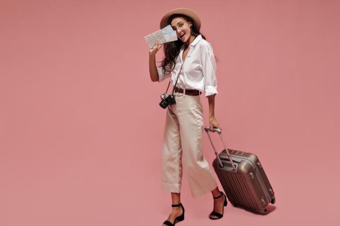 Woman with flight tickets in her hand and a suitcase looks happy