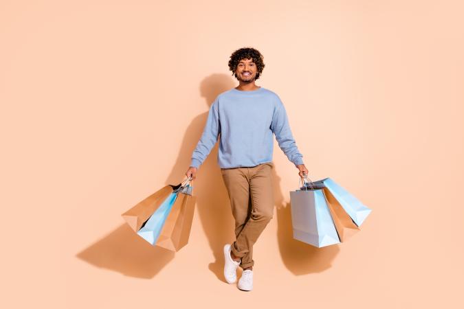 Young man smiling happily while holding multiple shopping bags